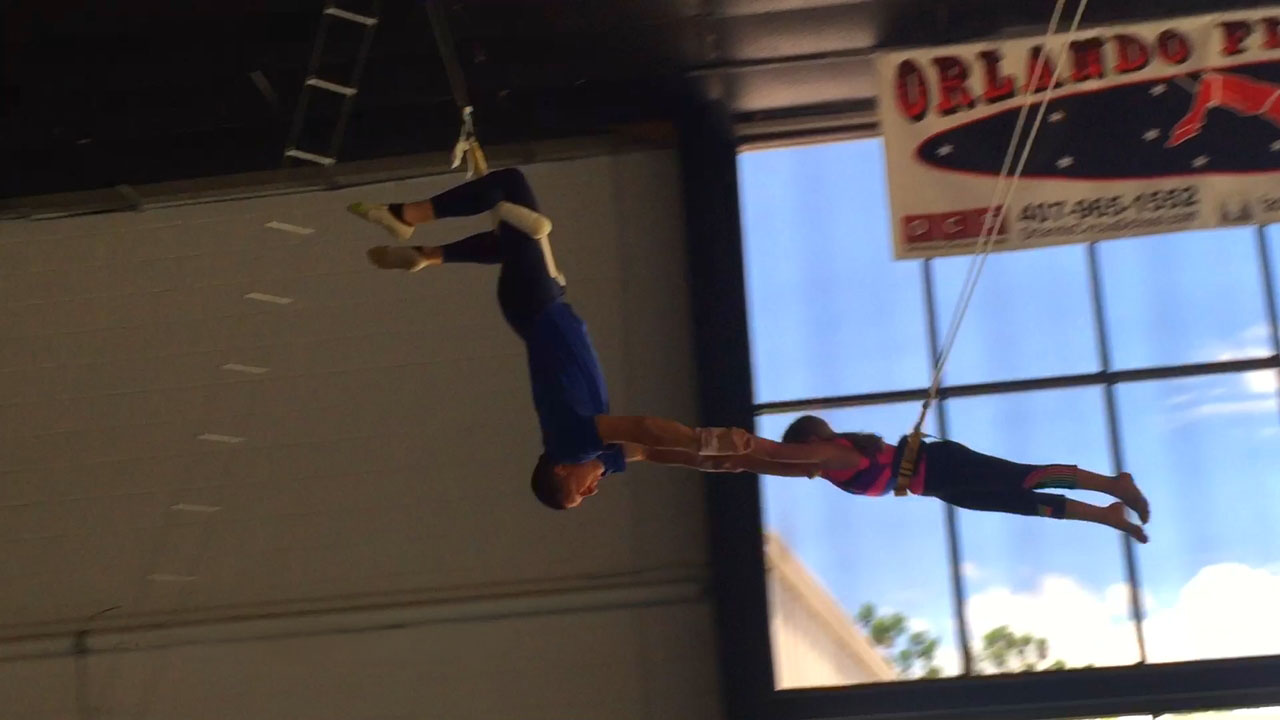 A flyer being caught mid-air on the flying trapeze near Universal Studios Orlando